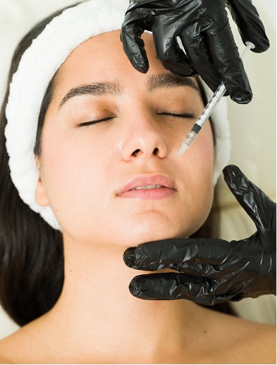 Model receiving an injection between the brows from a gloved provider