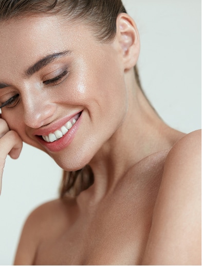 Smiling model with her hair pulled back, resting her cheek on her hand