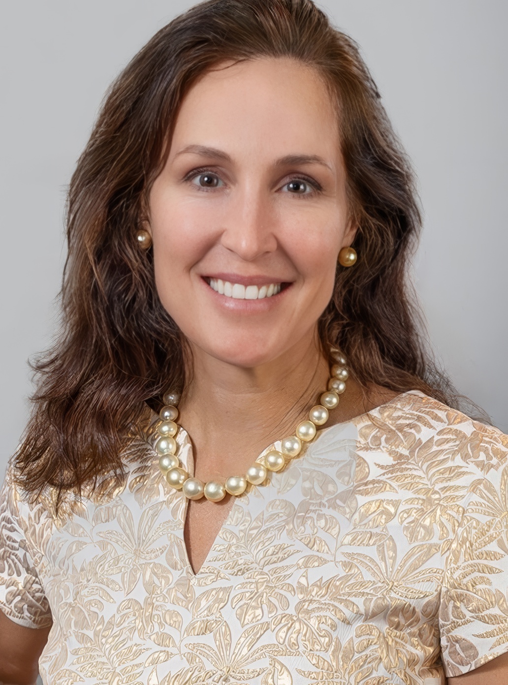 Dr. Corinne Horn, smiling, in a gold embroidered top and pearl necklace