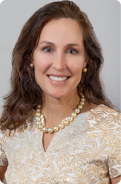 Dr. Corinne Horn, smiling, in a gold embroidered top and pearl necklace