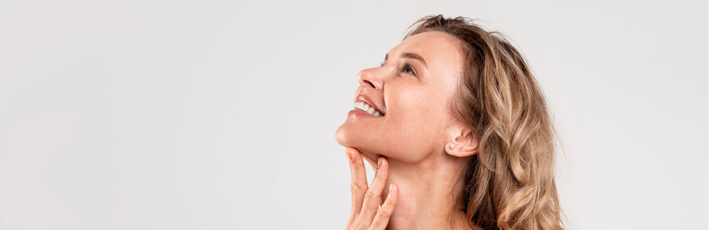 Model with her hair up, eyes closed, her hand along her jaw and neck