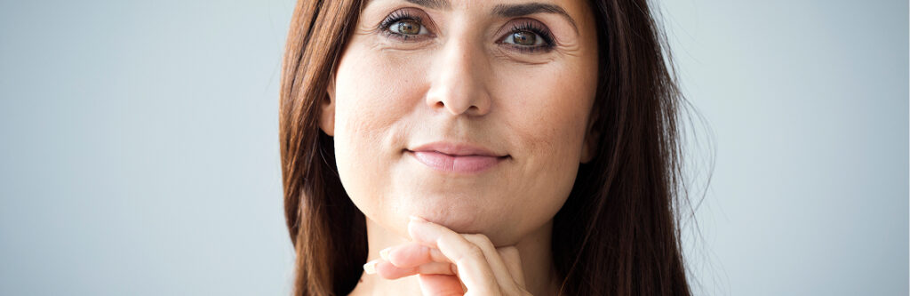 Smiling woman with long brown hair, her hand under her chin